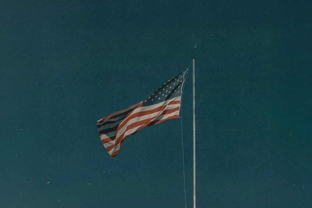 An American flag waving on a tall flagpole against a deep blue sky