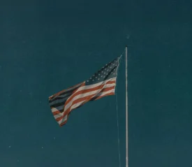 An American flag waving on a tall flagpole against a deep blue sky
