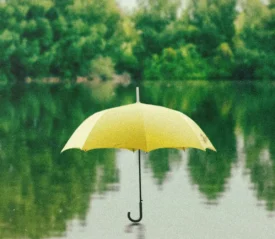 Single yellow umbrella sitting open on a body of water