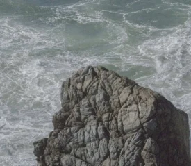 Large rock in the middle of crashing ocean waves