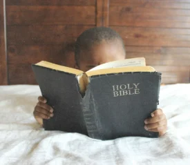 child reading the bible in bed