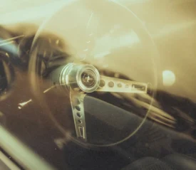 Vintage car steering wheel photographed through the windshield with warm golden reflections