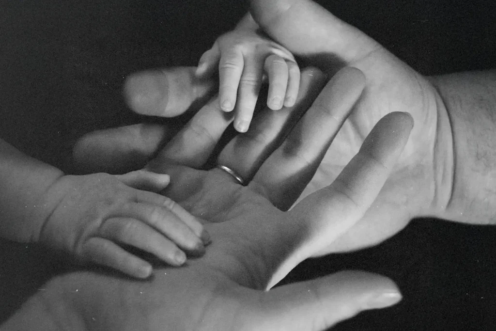 Two baby hands on top of two adult hands