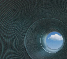Dark tunnel with circular rings leading to bright blue sky and clouds, symbolizing hope, escape, and freedom