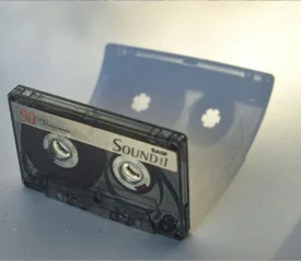 Cassette tape sitting upright with shadow reflecting on a white background