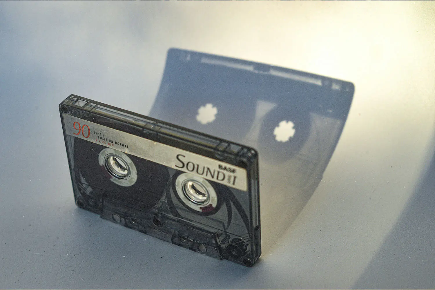 Cassette tape sitting upright with shadow reflecting on a white background