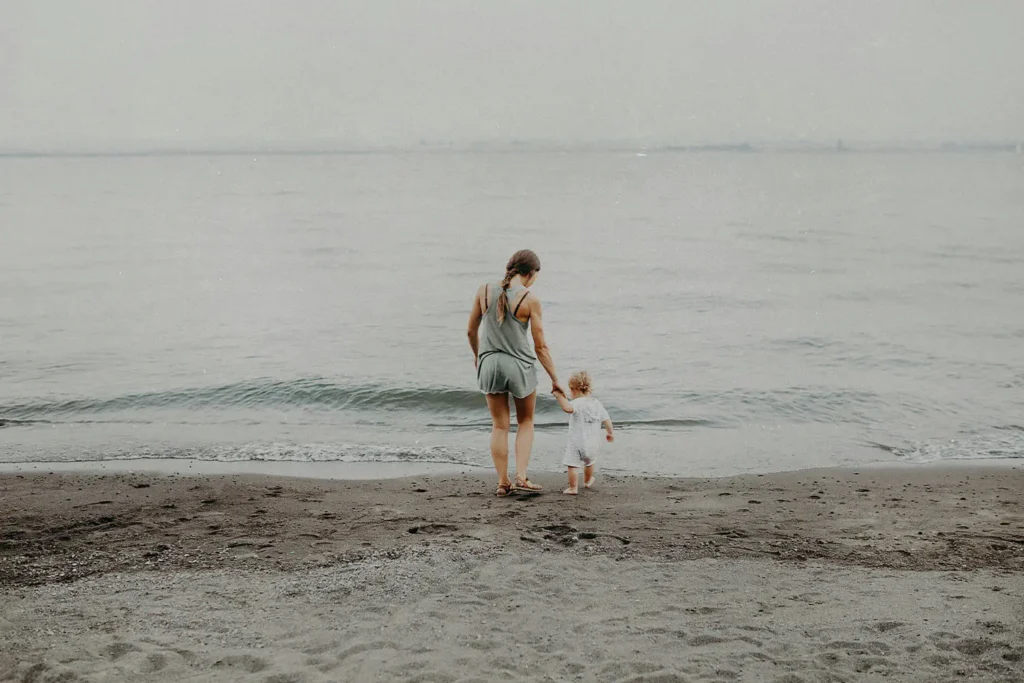 Mother walking on the shore with a child in hand into the sea