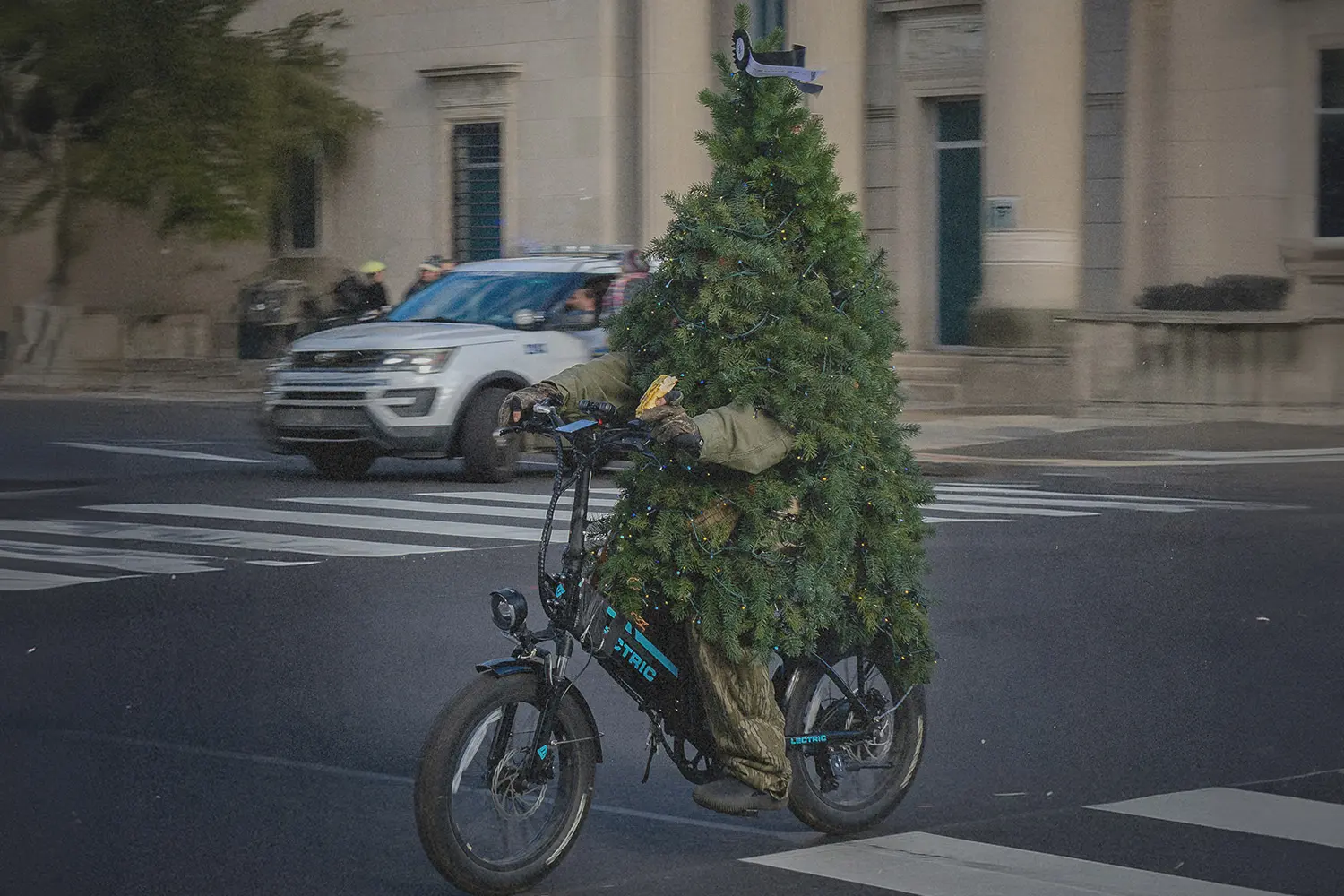 Beat Christmas stress with humor. See this festive image of a cyclist in a full Christmas tree costume navigating city streets.