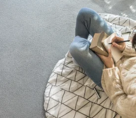 Woman writing in a notebook at a cozy desk, practicing gratitude journaling in a peaceful, softly lit room.