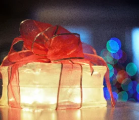 Glowing gift box wrapped with a red ribbon, symbolizing light, hope, and the message that Jesus transforms lives.