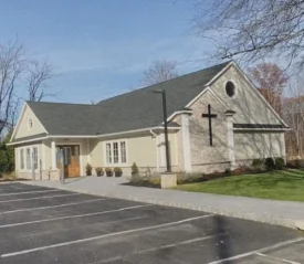 White church building with pitched roof and open parking lot