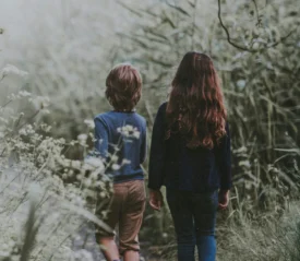Two children walking along a path through tall greenery, symbolizing guiding Children of God with spiritual authority in a scroll‑driven world today.