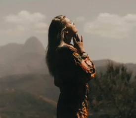 Silhouette of a person standing in a mountain landscape, reflecting on mental health and clearing mental clutter through renewing the mind and guiding thoughts.
