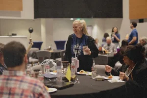 A group of people seated around a table during a shared meal in a conference or event setting.