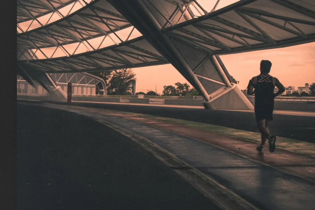 Runner training under a covered track at sunrise, symbolizing discipline, consistency, and mastering the fundamentals during a season of preparation and growth.