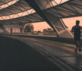 Runner training under a covered track at sunrise, symbolizing discipline, consistency, and mastering the fundamentals during a season of preparation and growth.